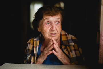 A touching portrait of an emotional elderly woman in her home, her face filled with deep expression...