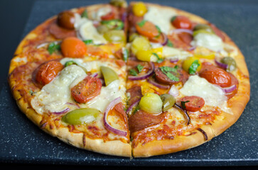 Homemade Pepperoni pizza on kitchen countertop, full size and sliced