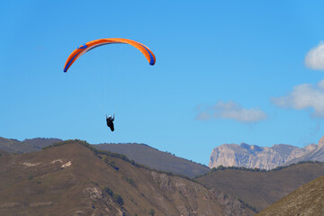 Flight of a paraglider in the rocky mountains. Chegem Aeroclub. Copy space.