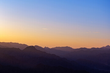 Serene mountain landscape at sunset with layered silhouettes of mountain