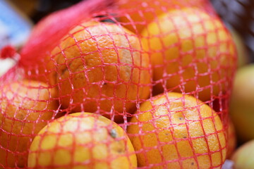 A collection of oranges stored in a bright red mesh bag for easy transport and display.
