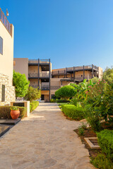 outdoor view of a resort area with stone pathways, lush greenery, and modern beige buildings