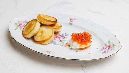Curd pancakes with yogurt and salmon caviar on a large white plate.
