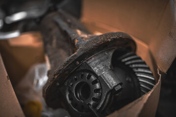 Disassembled differential of a 4x4 truck laying in a box in a garage.