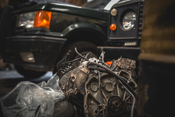 Disassembled V8 engine laying somewhere in a garage surrounded by random clutter © Pavel Babic