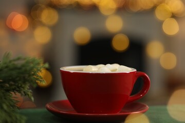 Tasty cocoa with marshmallows in cup and decor on table against blurred Christmas lights, closeup. Bokeh effect