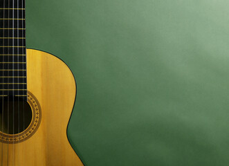 Acoustic guitar on green background, top view. Musical instrument