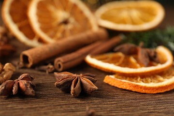 Different spices and dried orange slices on wooden table, closeup. Christmas season