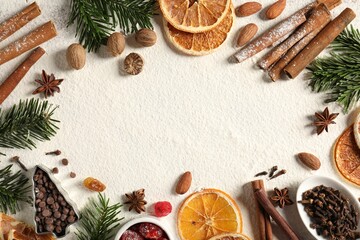 Frame of different aromatic spices and fir tree branches on table, flat lay with space for text. Christmas season