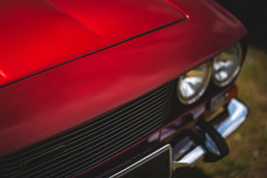 Close up view of a headlight and bonnet of a classic car.