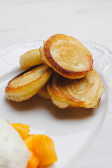 Appetizing cheese pancakes with mango and ice cream on a large white plate