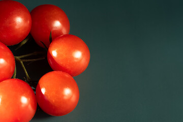 Cherry tomatoes on a branch on a dark green background