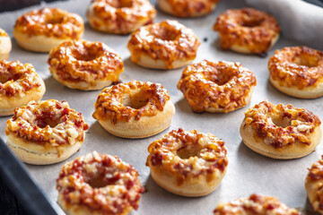 Mini pizza bagels on baking paper.