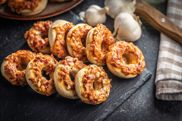 Mini pizza bagels on cutting board on black table.