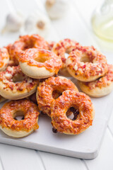 Mini pizza bagels on cutting board on white table.