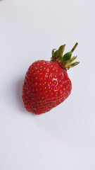 
Big single strawberry isolated on white background. Ripe red strawberry with shadow lies on the table, side view. Object for design. Vegetarian food.