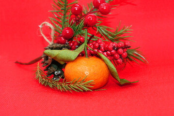 A spruce branch with a pine cone and a tangerine with leaves on a beautiful background, holiday, Christmas.