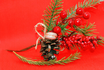 Wedding ring and a spruce branch with a pine cone on a red background, holiday, Christmas.