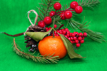 A spruce branch with a pine cone and a tangerine with leaves on a beautiful background, holiday, Christmas.