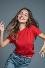 Fototapeta premium A young girl wearing a bright red shirt is dancing outdoors