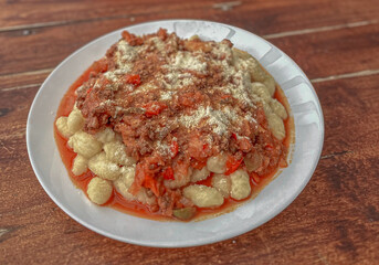 Bowl of potato gnocchi with bolognese sauce and cheese