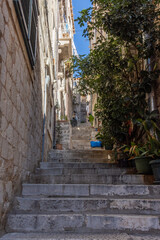 Dubrovnik, narrow street with wooden shutters, flowery balconies and warm lights. Steep stairs leading to small squares or churches. Croatia