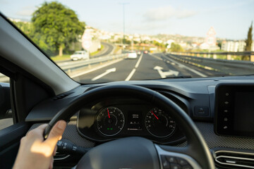 Driver view to the speedometer, with hand on the steering wheel. Blurred road. Madeira island, Portugal.