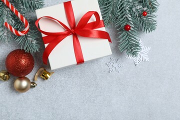 Beautiful gift box tied with bow and Christmas decorations on gray background 