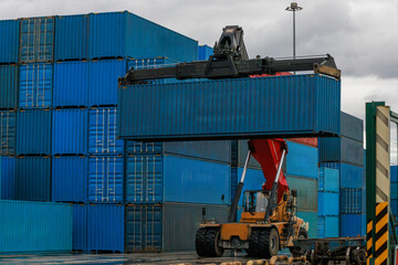 Reach stacker moves shipping container at port terminal.