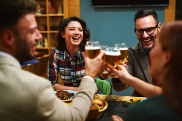Cheerful friends are toasting laughing and enjoying their time together during a meal at a restaurant