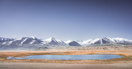 High mountain landscape panorama, a river in the mountains flows in a mountain valley among green meadows against the backdrop of mountains, landscape in the Pamir Mountains for background © Denis
