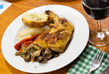 Tasty baked chicken legs and mushrooms at plate