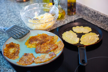 Frying potatoes pancakes at plate and in frying pan at home kitchen