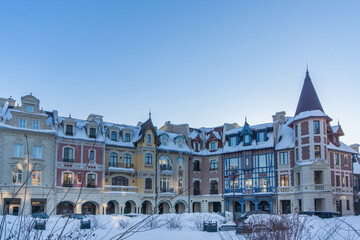 Naklejka premium Snow-covered historic buildings in a charming village under a clear blue sky during winter