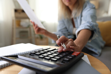 Budget planning. Woman using calculator while working with accounting document at table indoors,...