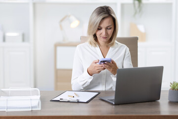 Businesswoman using smartphone at table in office