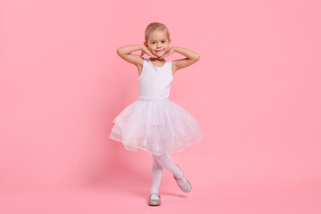 Little girl pretending to be ballerina on pink background. Dreaming of future profession