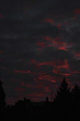 a dramatic sunset with vibrant red and orange hues streaking through a textured sky, silhouetting...