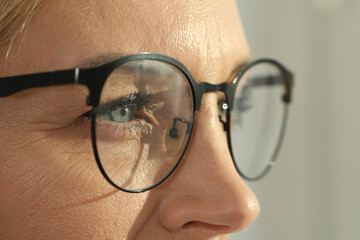 Woman wearing stylish glasses on blurred background, closeup