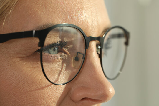 Woman wearing stylish glasses on blurred background, closeup