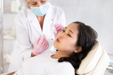 Skilled cosmetologist performing procedure for injecting beauty injections for the patient