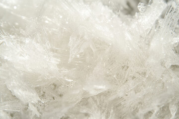 Textured snow close-up, fine crystalline details with sparkling white reflections under soft sunlight, cold and pristine