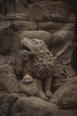 a finely crafted stone sculpture of a mythical creature resembling a lion with wings, perched on a rocky surface, showcasing intricate details in fur and feathers