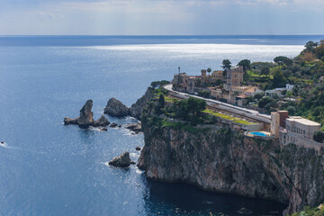 View at cliff on the coastline in Taormina with clear turquoise water at the mediterranean sea on a sunny day, Sicily, Italy