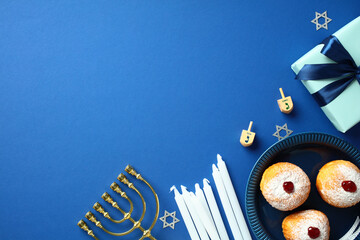 Hanukkah traditional symbols - menorah, dreidels, sufganiyot on blue background. Happy Chanukah...