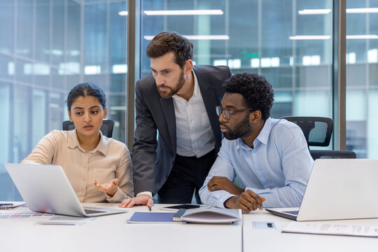 Business meeting with diverse colleagues working together on laptops in modern office. Team collaboration, problem-solving, brainstorming new ideas. Business meeting, teamwork, office, laptop