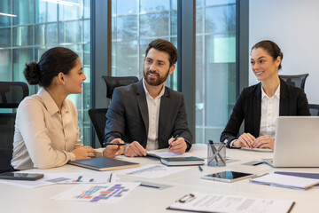 Team in office engaged in meeting discussing strategies. Professionals collaborate around table...