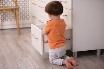 Little boy playing with kitchen appliances indoors. Dangerous situation