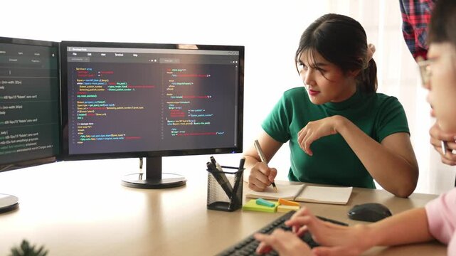 Slow motion back end software developer engineer for computer programming working together on debugging writing computing code, solving complex algorithms display on monitor in office. Burgeoning