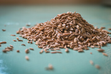 Heap of cumin ready to cook on turquoise background
